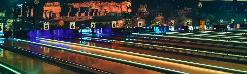 An empty, dim bowling alley, with Italian imagery and signage on the backdrop.